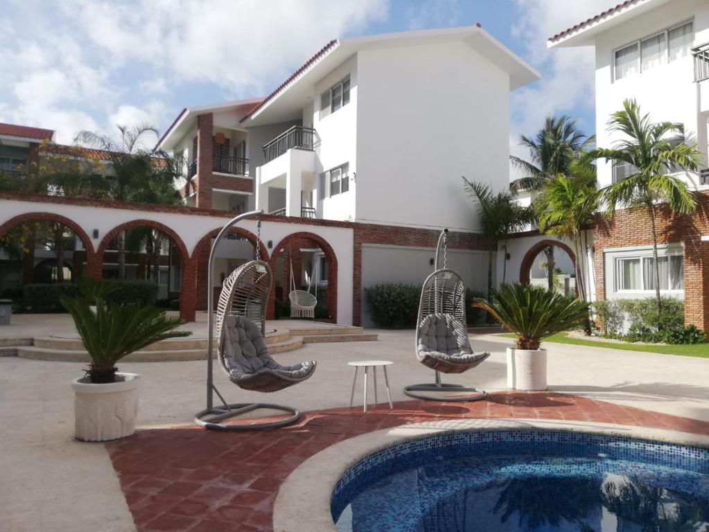 a house with a swimming pool and chairs next to a building at Coral Village - "Caribbean Cocktails" Deluxe Suites & Pool in Punta Cana