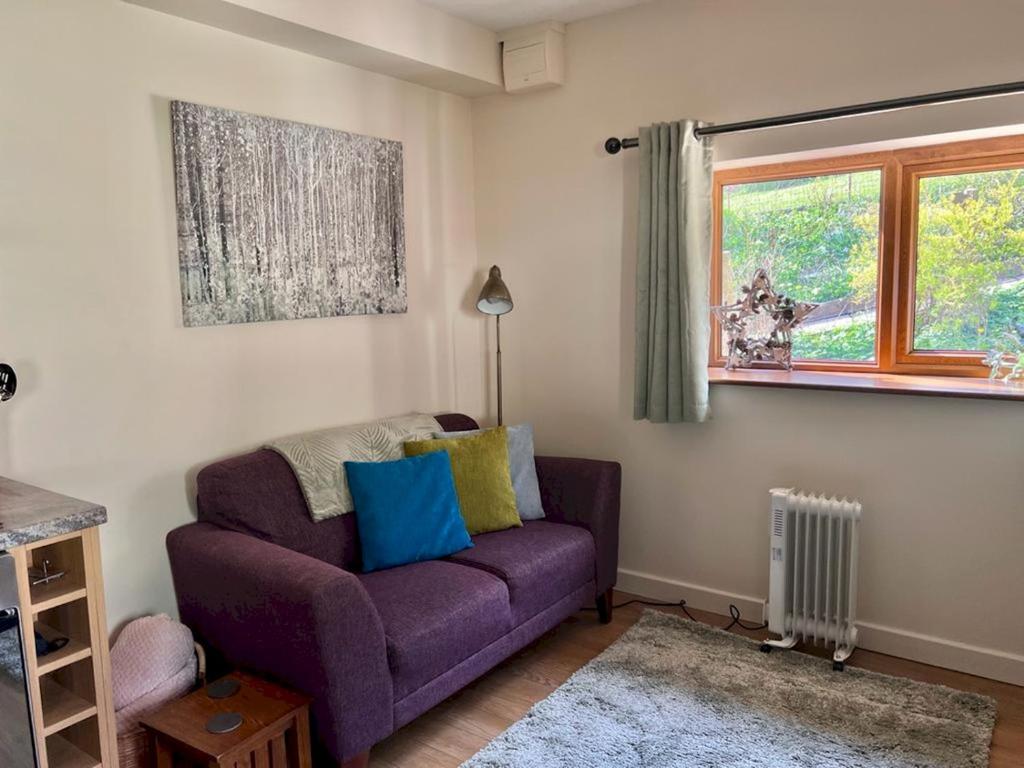 a purple couch in a living room with a window at Pass the Keys The Pumphouse Holiday Cottage in Kidwelly