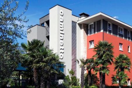 a hotel building with palm trees in front of it at Albergo Al Caminetto in Nago-Torbole