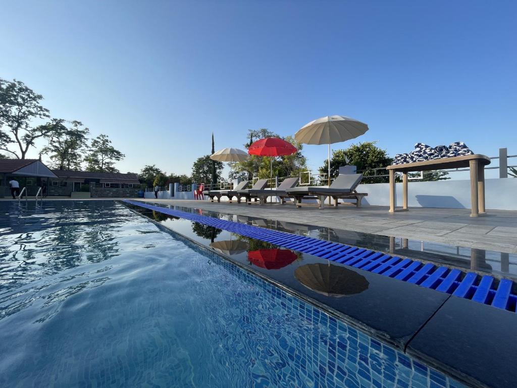 a swimming pool with umbrellas and a table and chairs at The B Hive in Londa