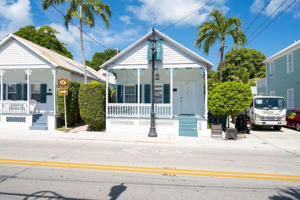 a white building with a clock in front of a street at Just steps to Duval- Sleeps 10- Heated Pool House in Key West