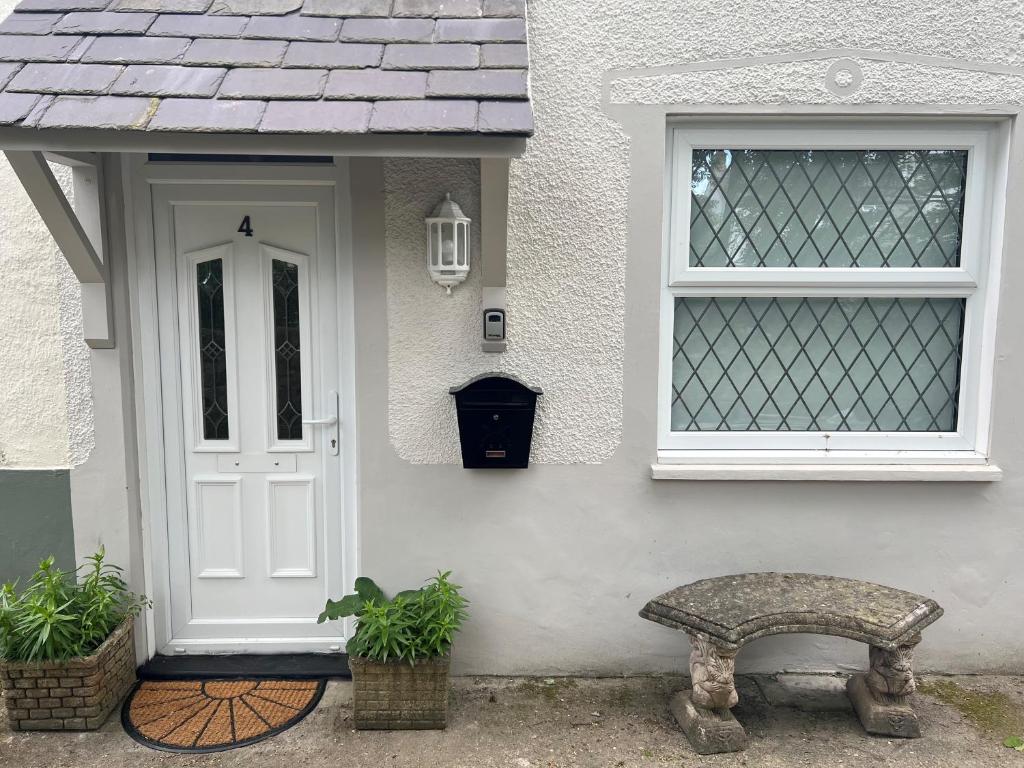 uma porta branca e um banco em frente a uma casa em 4 Railway Terrace em Conwy