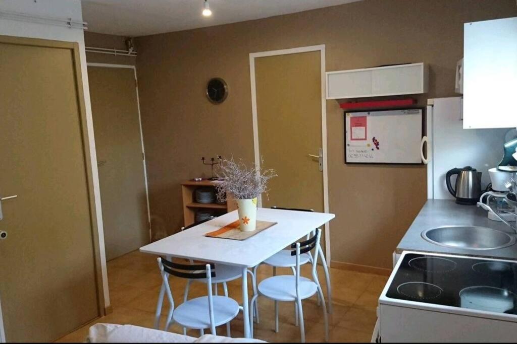 een kleine keuken met een witte tafel en stoelen bij Petite dépendance in Isneauville
