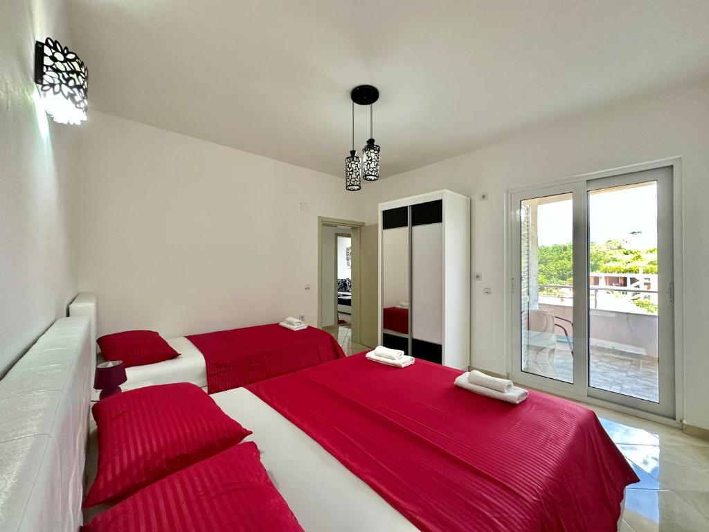 two beds in a white room with red sheets at Queen Kodre Apartments in Ulcinj