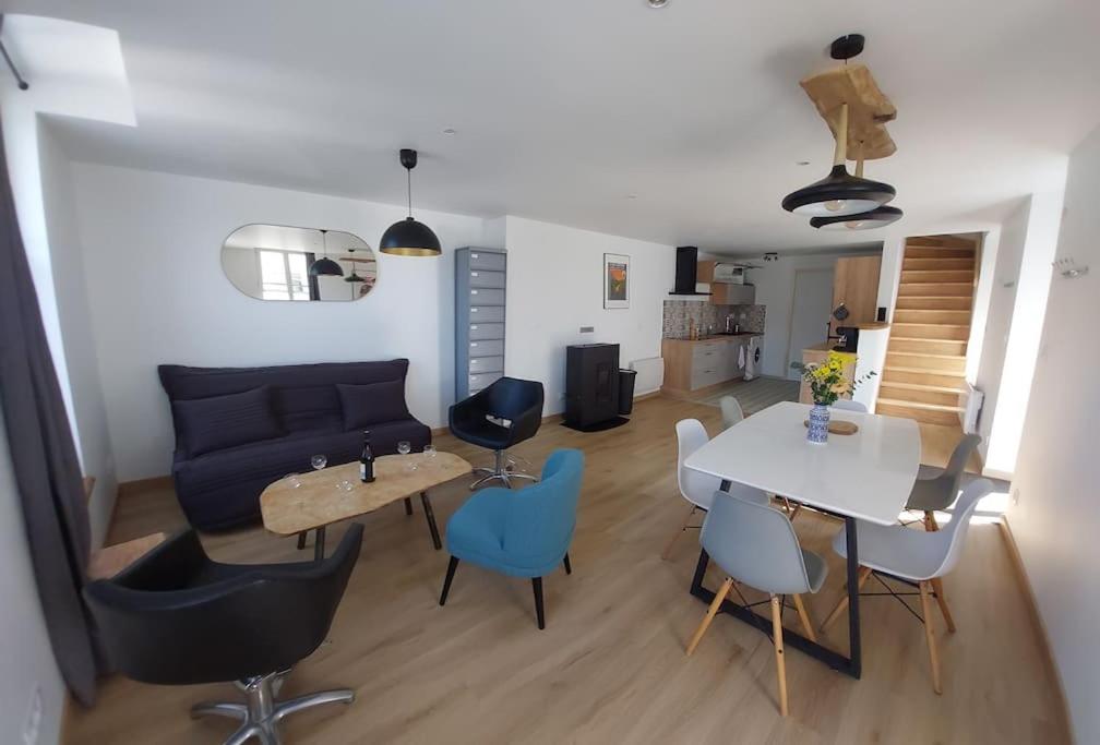 ein Wohnzimmer mit einem Sofa, einem Tisch und Stühlen in der Unterkunft La Cigogne, moderne, spacieux et bien placé in Thury-Harcourt