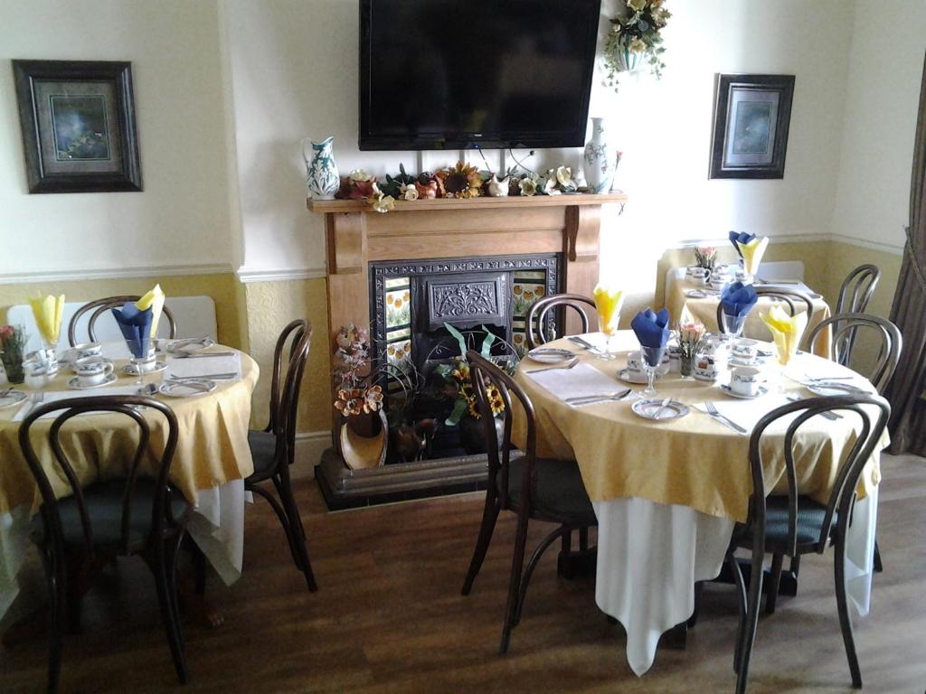 a dining room with two tables and a fireplace at No. 9 Guest House in Llandudno