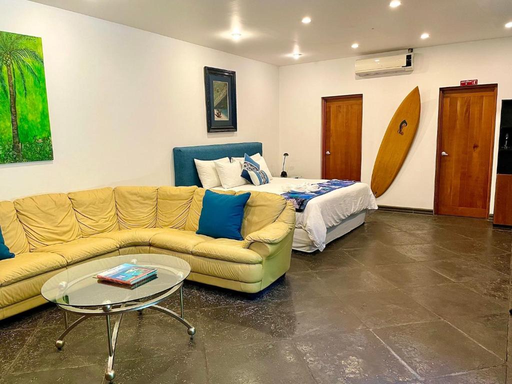 a living room with a couch and a bed and a surfboard at Suite 9, Manuel Antonio in Quepos