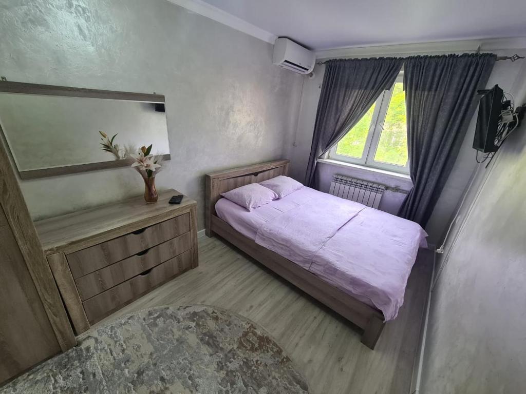 a small bedroom with a bed and a window at Апартамент Плаза in Shymkent
