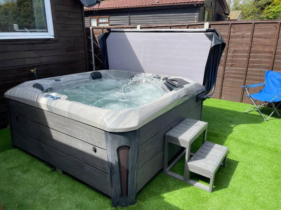 a large hot tub with a bench and a chair at Whittams Hot-tub Chalet Retreat in Heysham