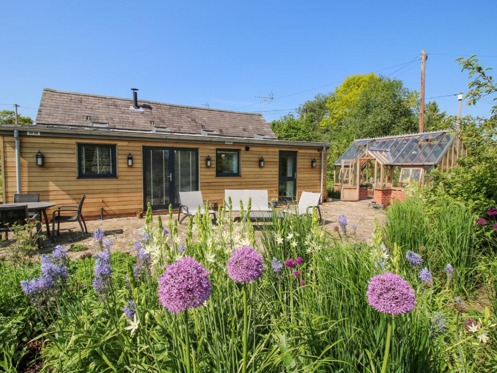 a log cabin with a garden and flowers at The Mission Room in Malpas