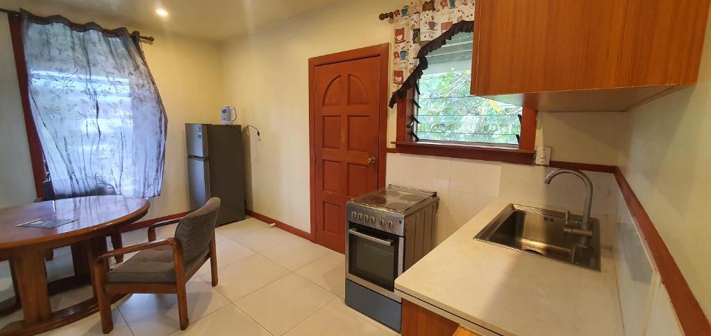 a kitchen with a sink and a table and a refrigerator at Lynn's Getaway Apartments in Apia