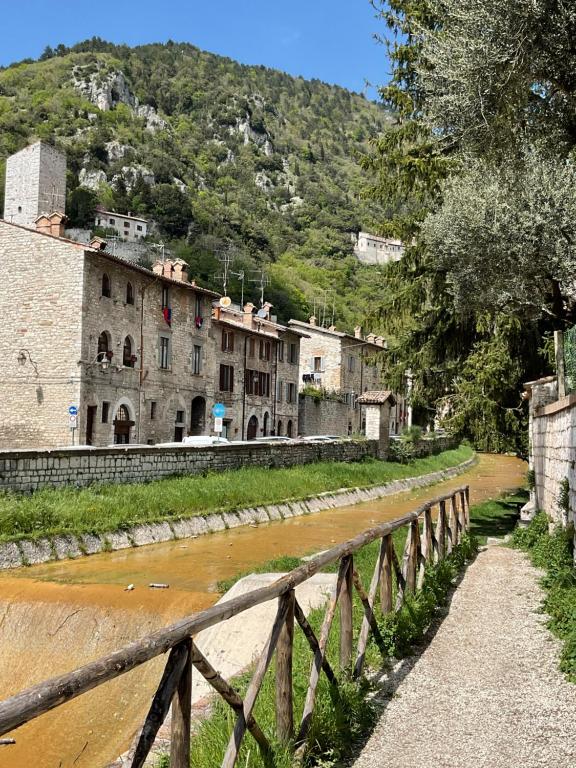 a bridge over a river with buildings and a mountain at Raphael house in Gubbio