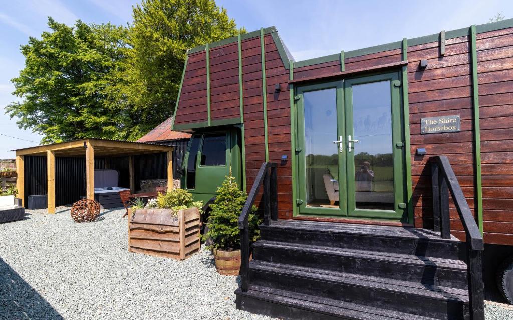 uma pequena casa com uma porta verde e escadas em The Shire Luxury Converted Horse Lorry with private hot tub Cyfie Farm em Llanfyllin
