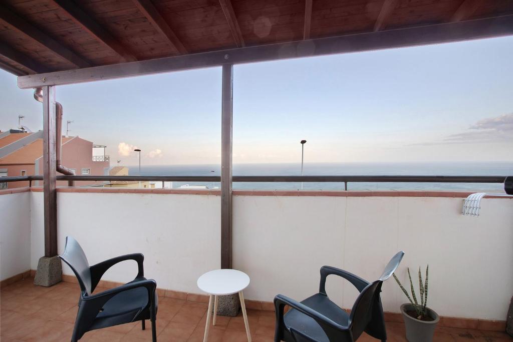 a balcony with chairs and a table and a view of the ocean at Vista Horizonte in Barranco Hondo