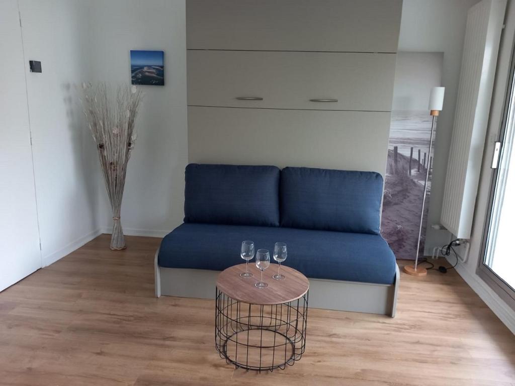 un canapé bleu dans un salon avec une table dans l'établissement Studio T1 bis calme au centre du Moulleau, à Arcachon