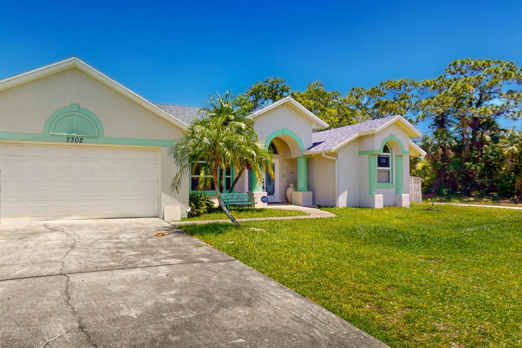 uma casa branca com uma garagem e uma palmeira em Happy Beachy Casa em Fort Pierce