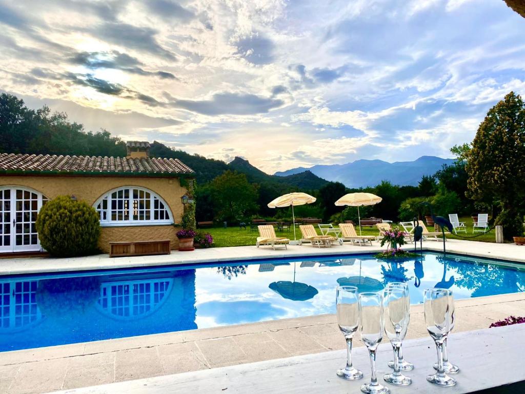 una piscina con copas de vino frente a una casa en Masia Mimosa Pool house, en Darnius