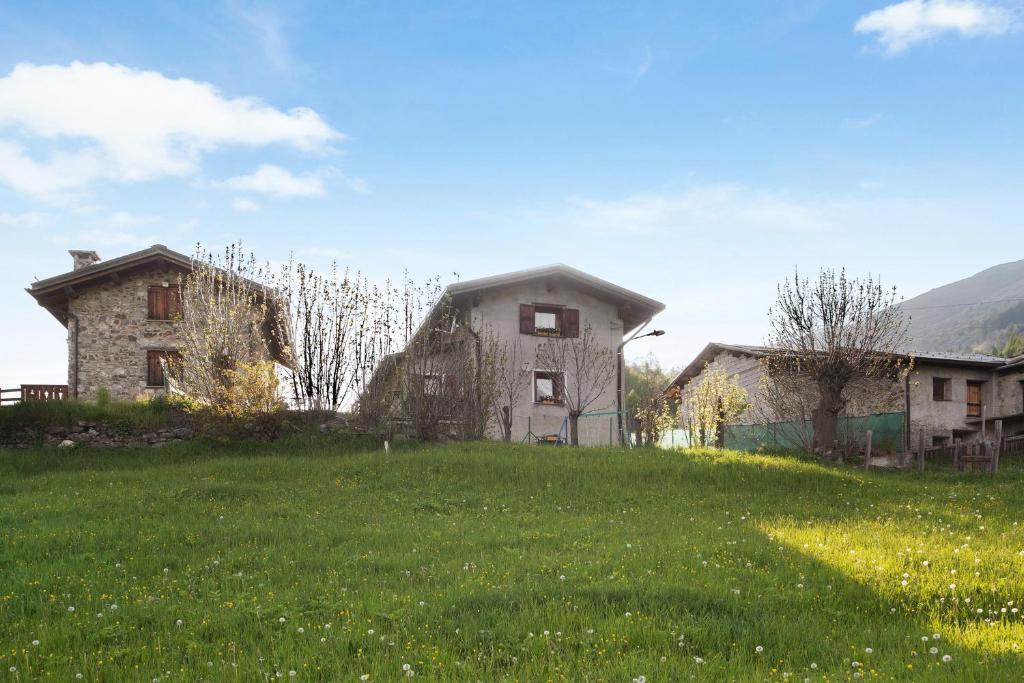 an old house on a grassy field with two buildings at Dolce Casa vicino a Bormio in SantʼAntonio