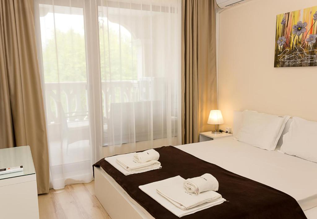 een slaapkamer met een bed met twee handdoeken erop bij Coastal 1BD Flat with Pool & Parking in Varna