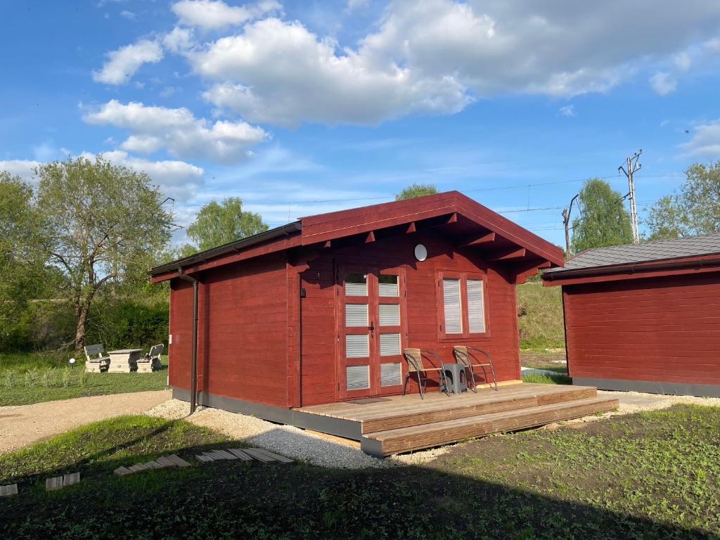 a small red building with a wooden deck at WOMOCAMP Holzhütte 1 in Saulkrasti