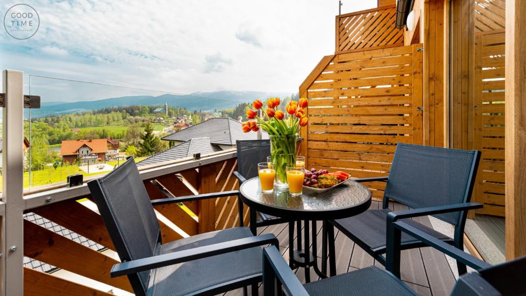 d'un balcon avec des chaises et une table ornée d'un vase de fleurs. dans l'établissement Apartamenty Good Time - Przy Dolinie Szczęścia, à Szklarska Poręba