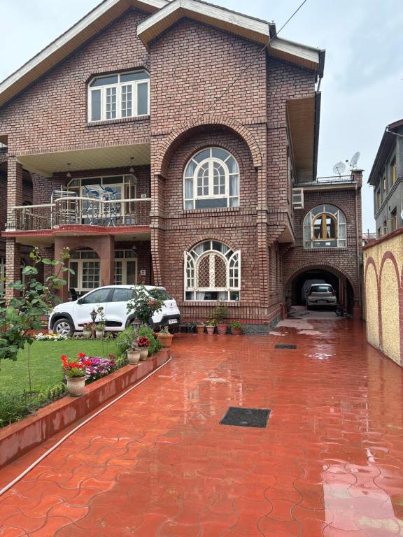 a brick house with a driveway in the rain at Taha Inn Home comfort in Srinagar
