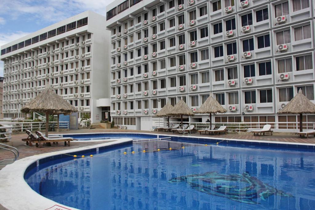 a hotel with a large swimming pool in front of a building at Hippocampus Vacation Club in Pampatar