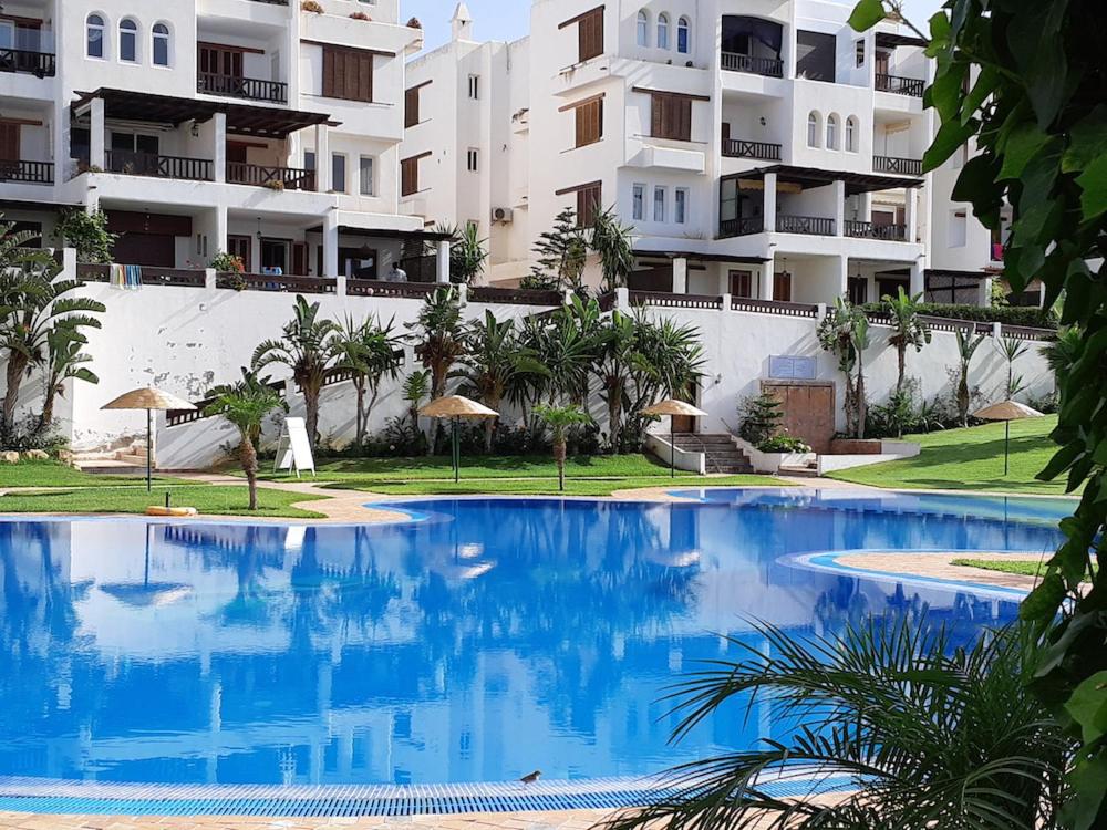 a large blue swimming pool in front of a building at Appartement de vacances piscine et plage de Cabo Negro in Cabo Negro