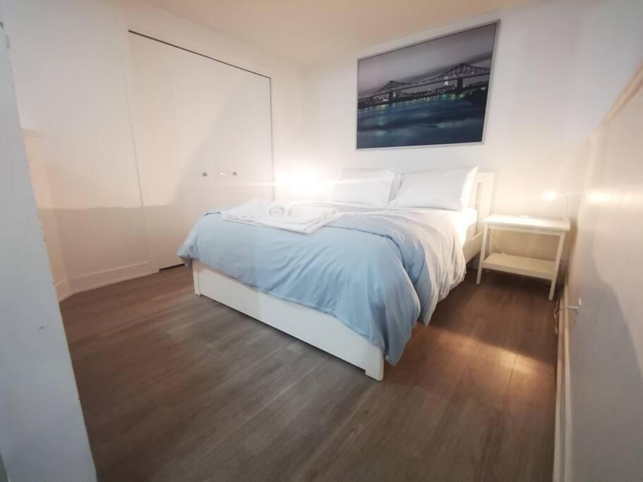 ein weißes Schlafzimmer mit einem Bett und einem Nachttisch in der Unterkunft Lovely studio in Longueuil, near Downtown Montreal in Longueuil