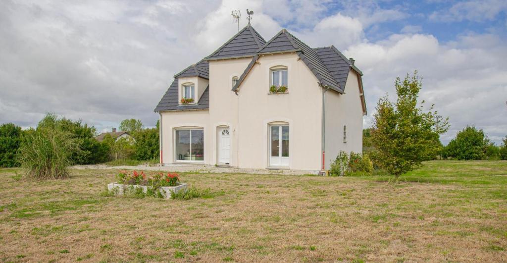 a white house with a black roof in a field at Au clair de lune in Saint-Rémy-sous-Barbuise
