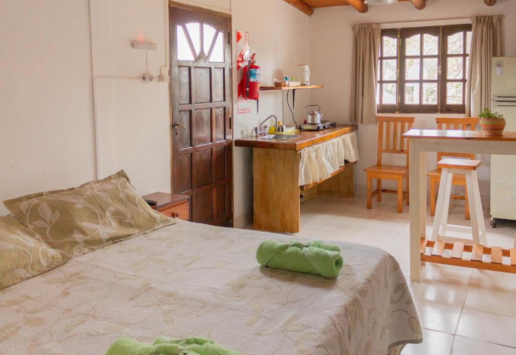 1 dormitorio con 1 cama y cocina con mesa en Monoambiente Colibrí en Capilla del Monte