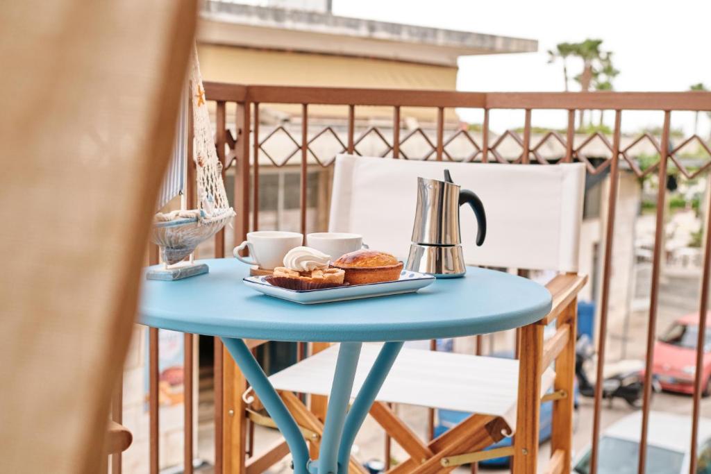 een blauwe tafel met koffie en gebak op een balkon bij Conchiglia & Medusa Home Otranto in Otranto