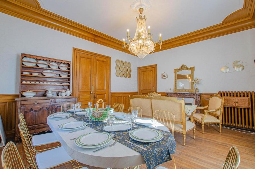 a dining room with a table with chairs and a chandelier at L'instant champenois & son annexe in Bréviandes