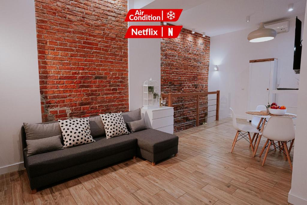 ein Wohnzimmer mit Sofa und Ziegelwand in der Unterkunft Old Town WAWEL Premium Apartment - 60m2 in Krakau