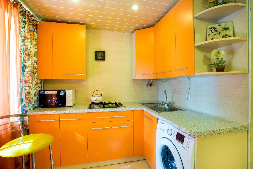 a kitchen with orange cabinets and a washing machine at Sun in the City Center in Kherson