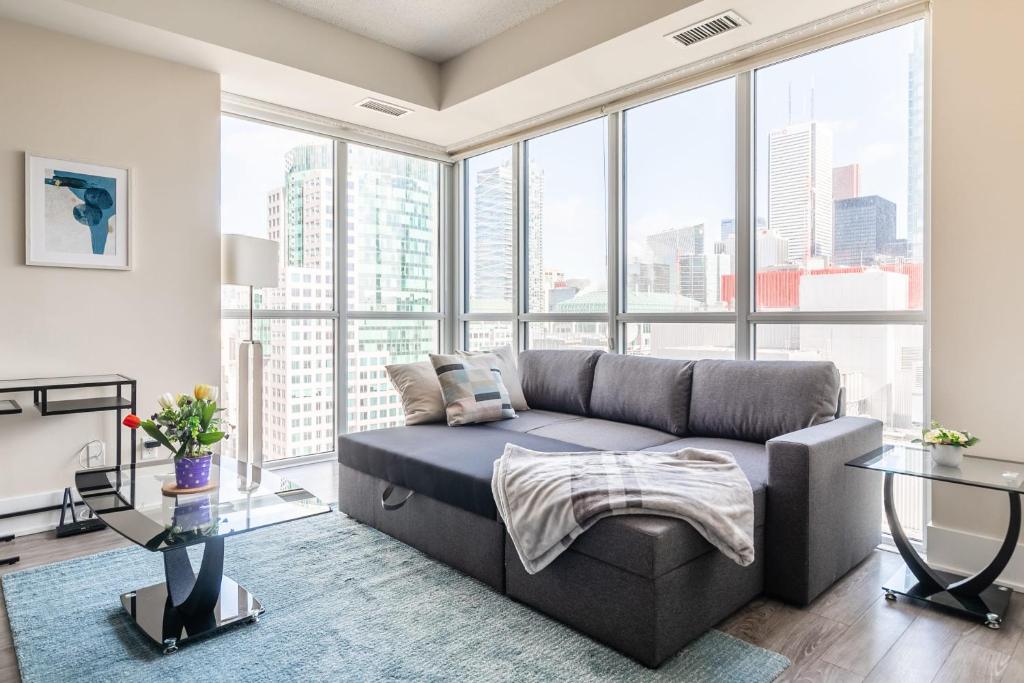 een woonkamer met een bank en grote ramen bij Luxury 1BR Condo - King Bed - Stunning City View in Toronto