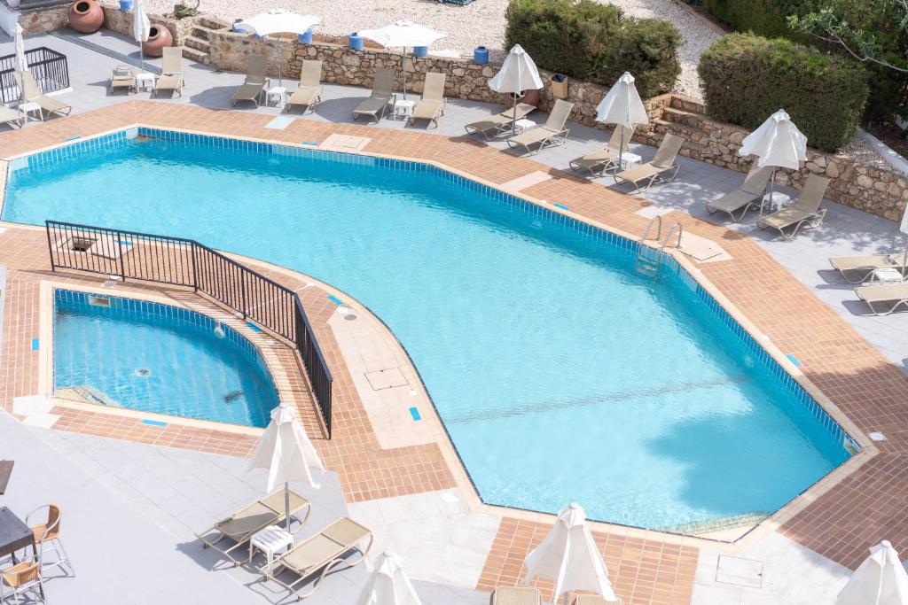 einen Blick über einen Pool mit Stühlen und Sonnenschirmen in der Unterkunft Flora Hotel Apartments in Protaras