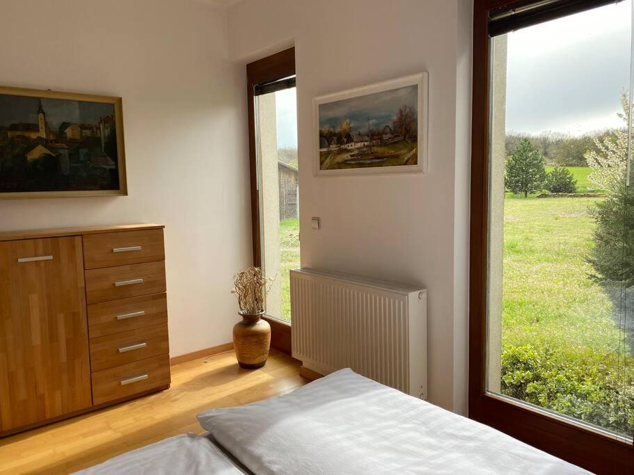 a bedroom with a bed and a large window at Szent Kard Vendégház in Sóly