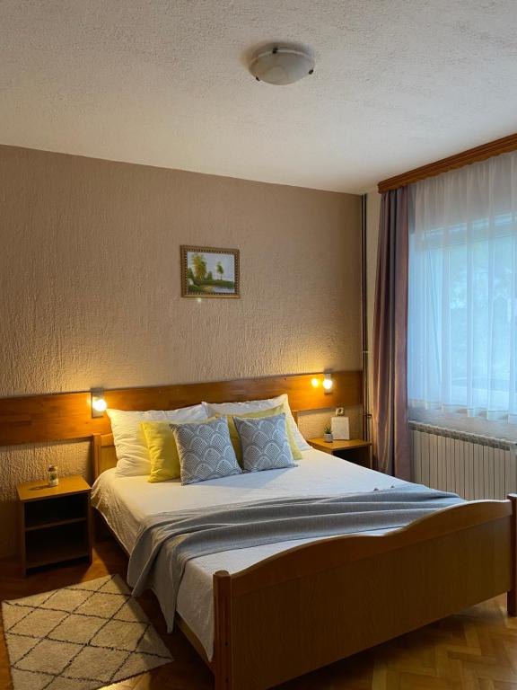 1 dormitorio con 1 cama con 2 mesas y una ventana en M&N Zafran, en Grabovac