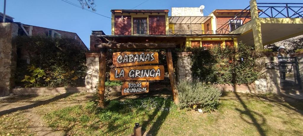 a sign in front of a building with a house at Cabañas La Gringa in Potrero de los Funes