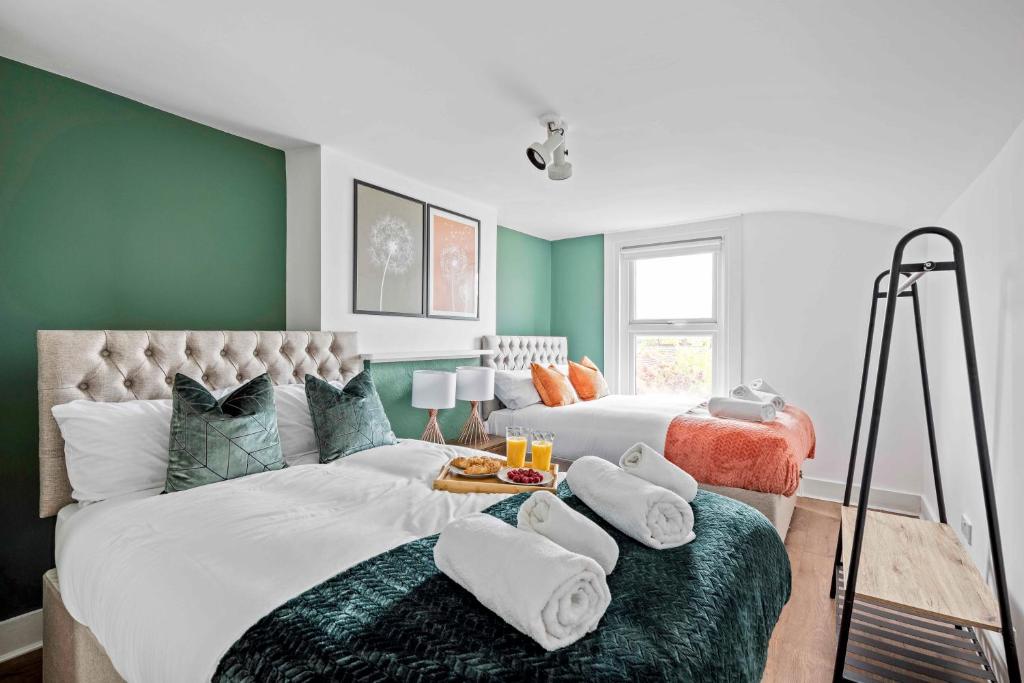 um quarto com 2 camas e paredes verdes em Parea Living - Hackney, 4-Bedroom Victorian House w Big Garden em Londres