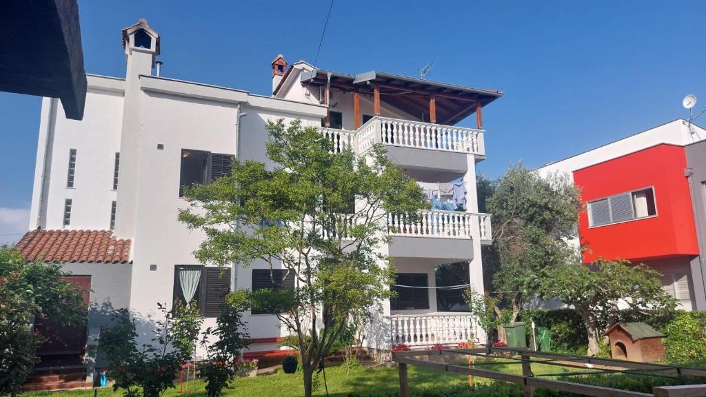 a white building with a balcony and a red building at Iva in Zadar