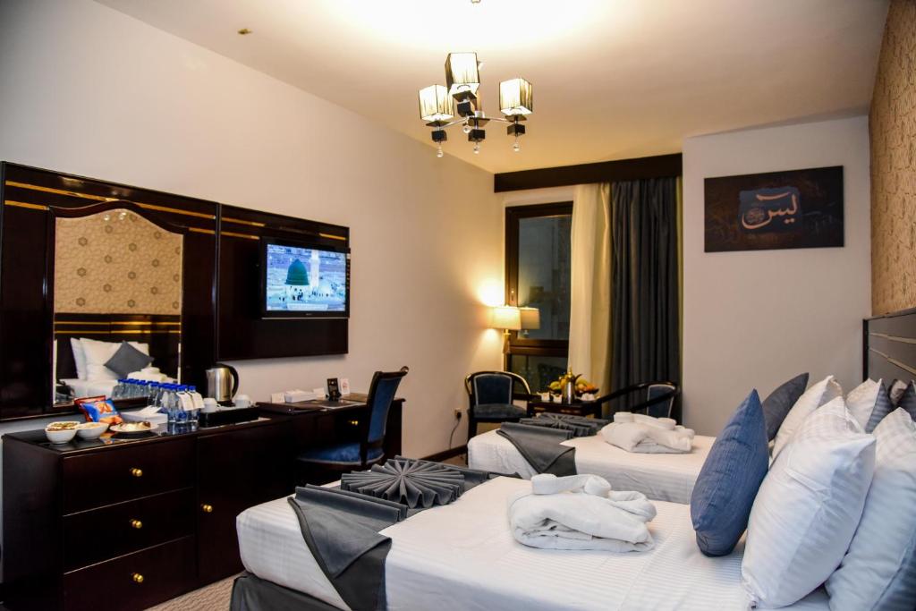 a hotel room with two beds and a desk at Grand Plaza Badr Al Maqam in Al Madinah