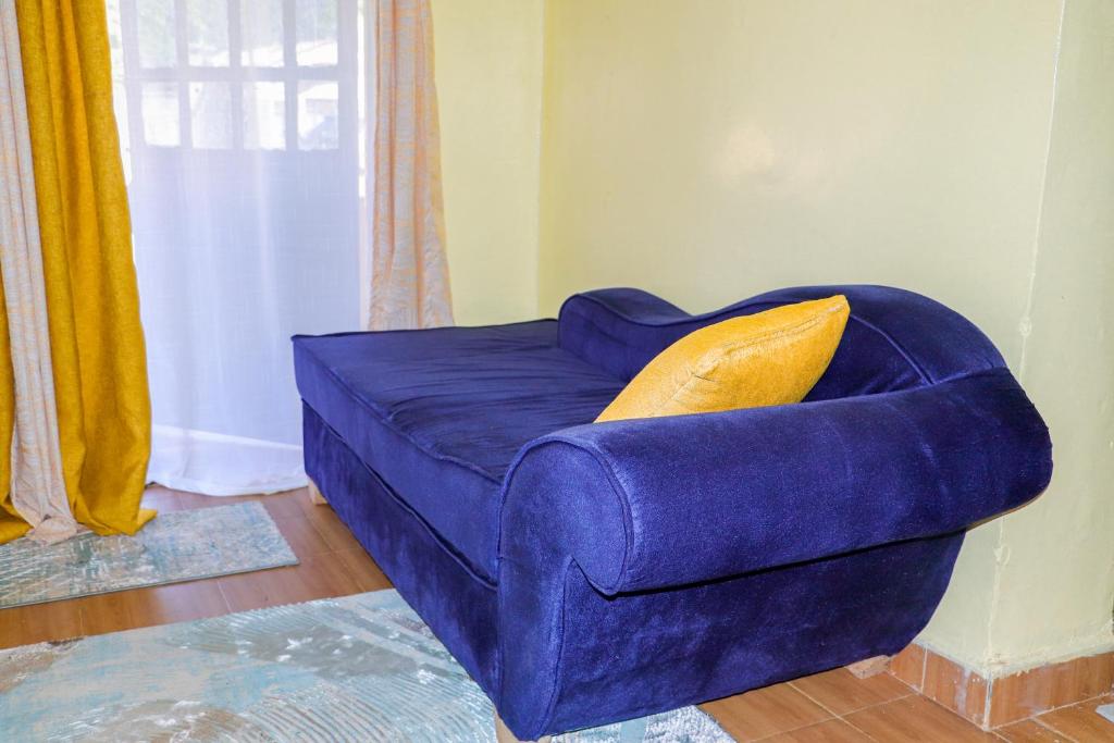 Sofá azul con almohada amarilla en una habitación en Trendy Homes Studio BnB, en Bungoma