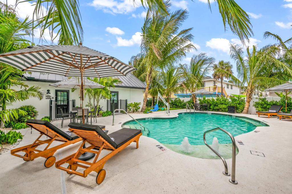 a swimming pool with two chairs and an umbrella at The Retreat at Anna Maria Island Inn in Bradenton Beach