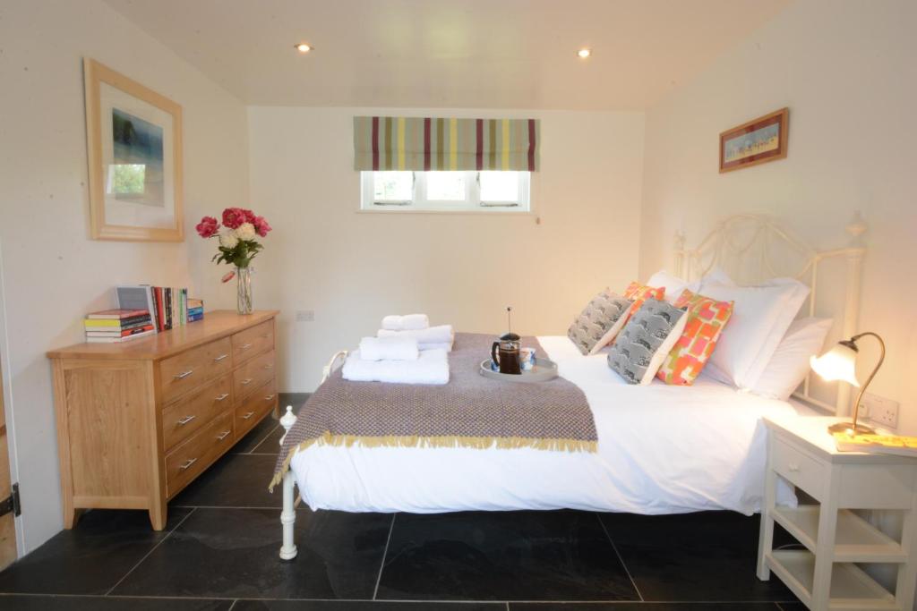 ein Schlafzimmer mit einem weißen Bett mit einer Kommode und einer Schublade in der Unterkunft Yew Tree Farm Stable, Worlingworth in Worlingworth