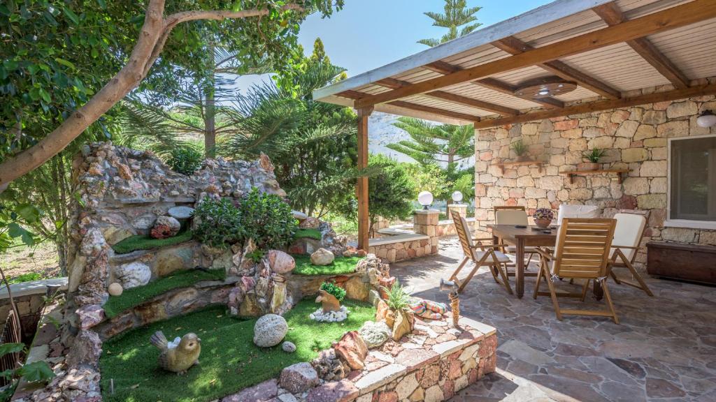 a patio with a table and chairs and a stone wall at Emilia's Little Farmhouses in Agii Anargiri Milos