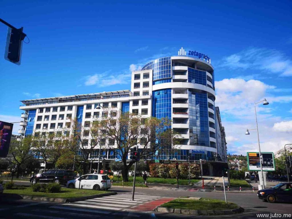 een hoog gebouw met auto's geparkeerd voor het bij Great location two bedroom apatment ''MAXIM'' in Podgorica