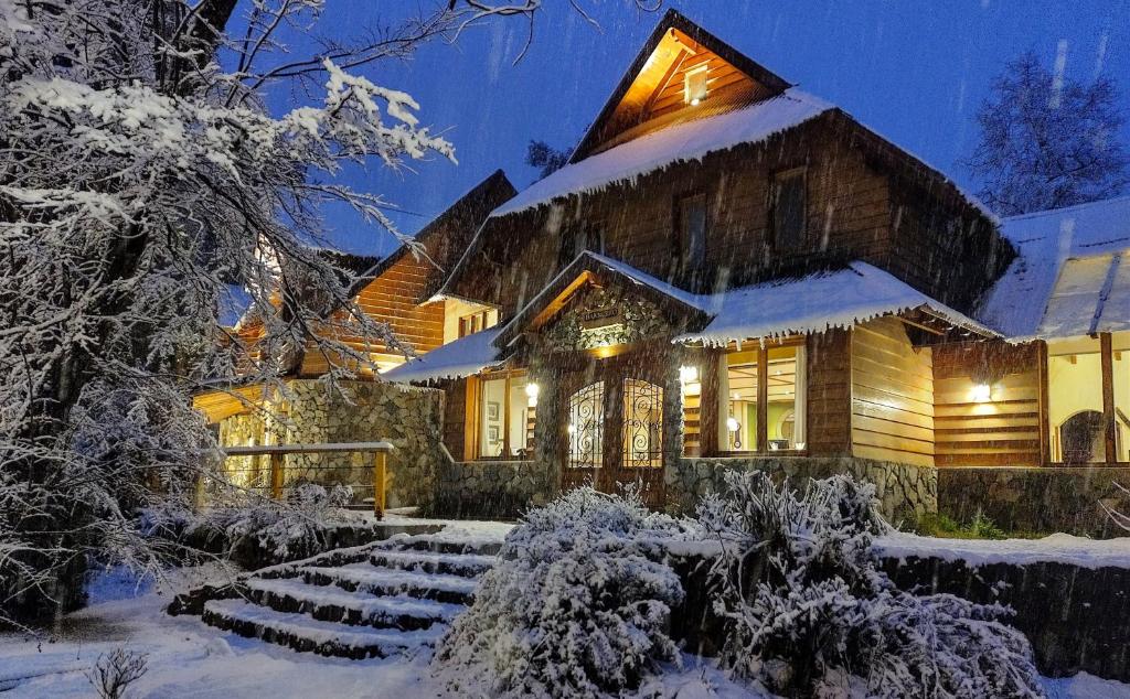 un hogar en la nieve por la noche en Hostería Bajo Cero en Villa La Angostura