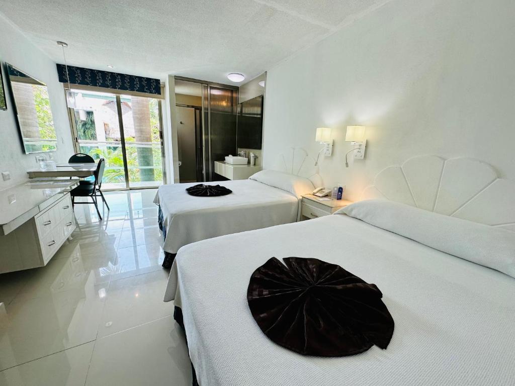 una habitación de hotel con 2 camas y una sombrilla negra. en Hotel Plaza Caribe, en Cancún